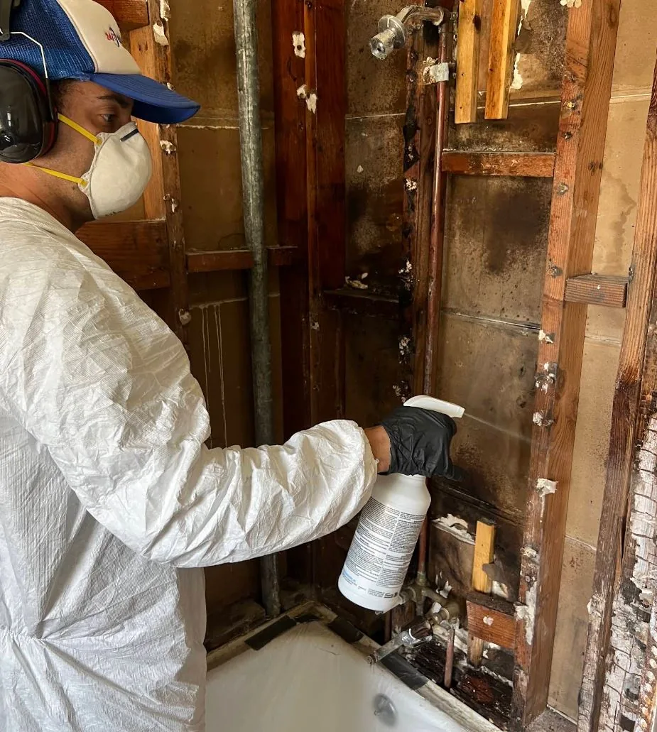 Water damage technician working inside an affected wall cavity in Los Angeles